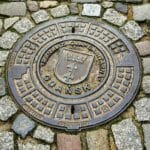 Kanalizacja miasta Gdańsk na okrągłej pokrywie w brukowanej ulicy