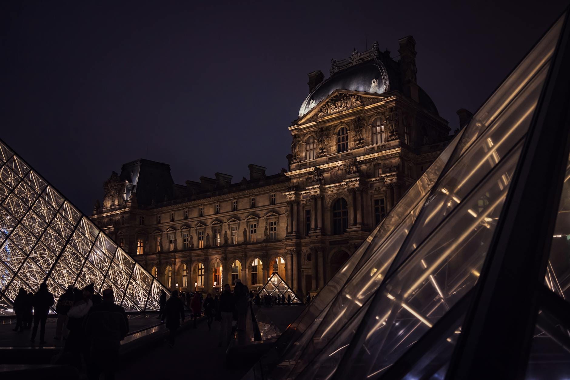 Nocne iluminacje piramid przed Luwrem w Paryżu