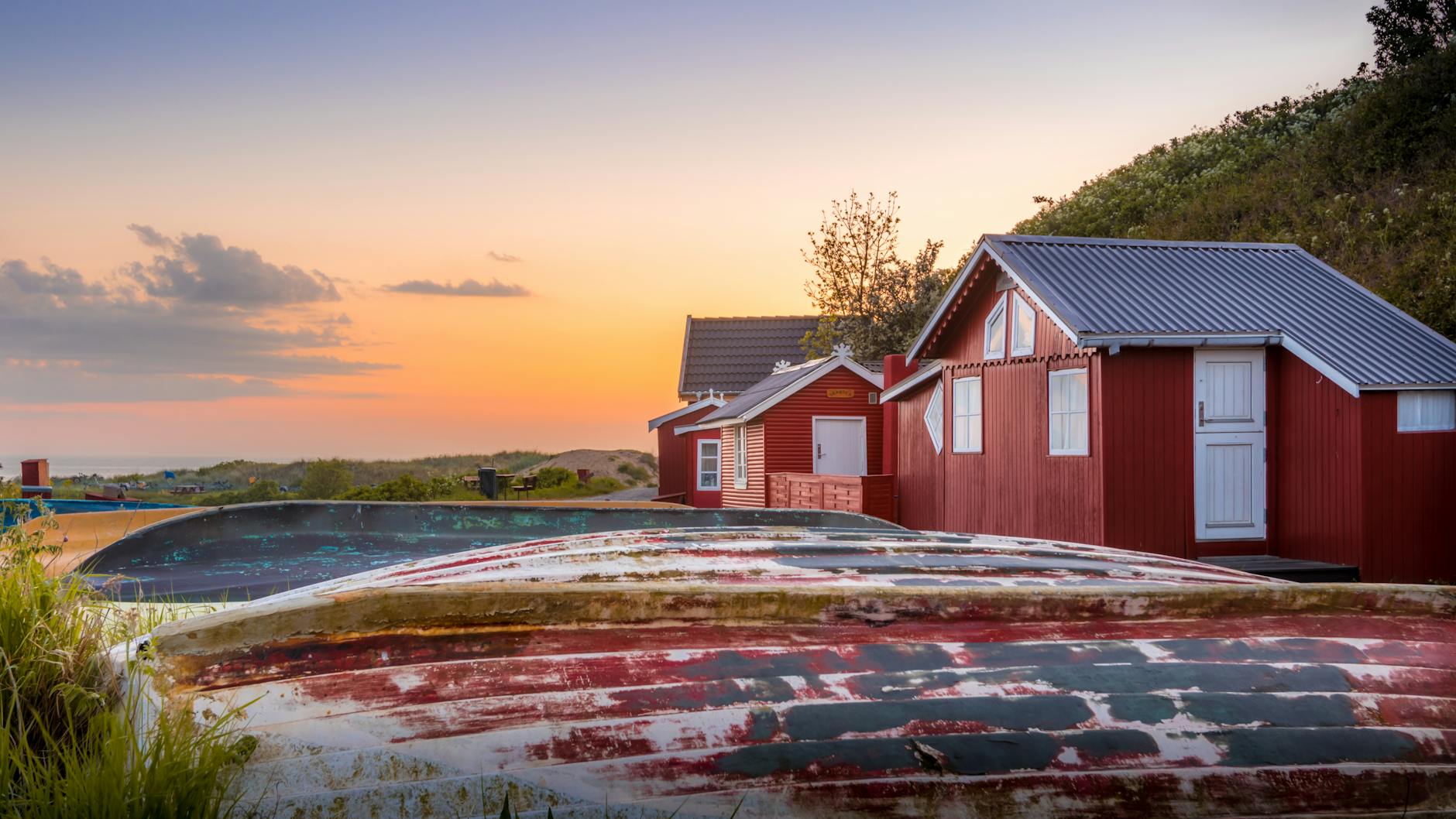 Czerwone drewniane domki nad spokojną wodą o zachodzie słońca