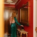 Kobieta w błyszczącej sukience w lustrze eleganckiego hotelowego pokoju