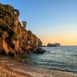 Zachód słońca nad skalistymi klifami i spokojnym morzem na plaży