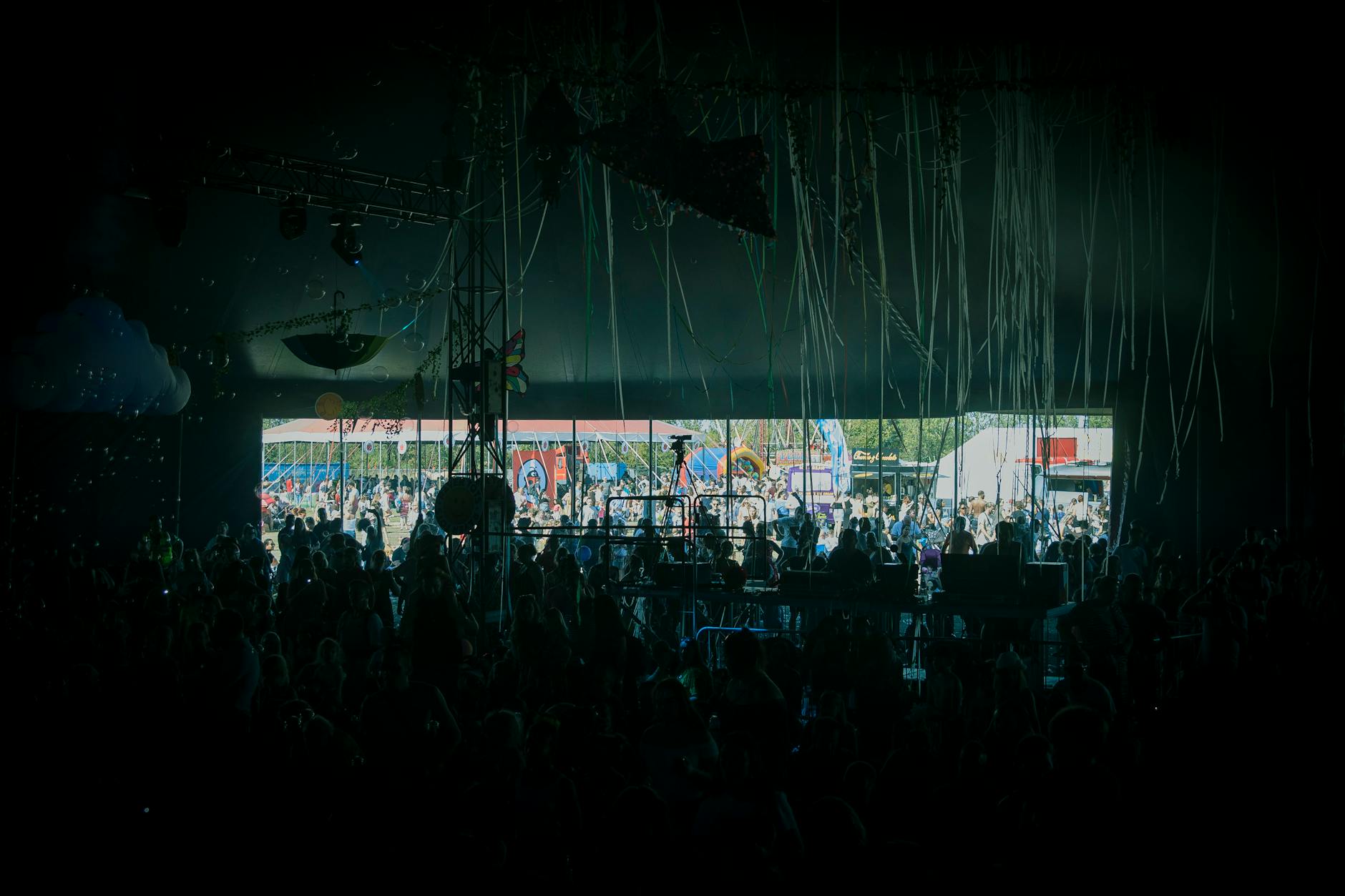 Tłum festiwalowiczów bawiący się przy koncercie na kolorowej scenie plenerowej